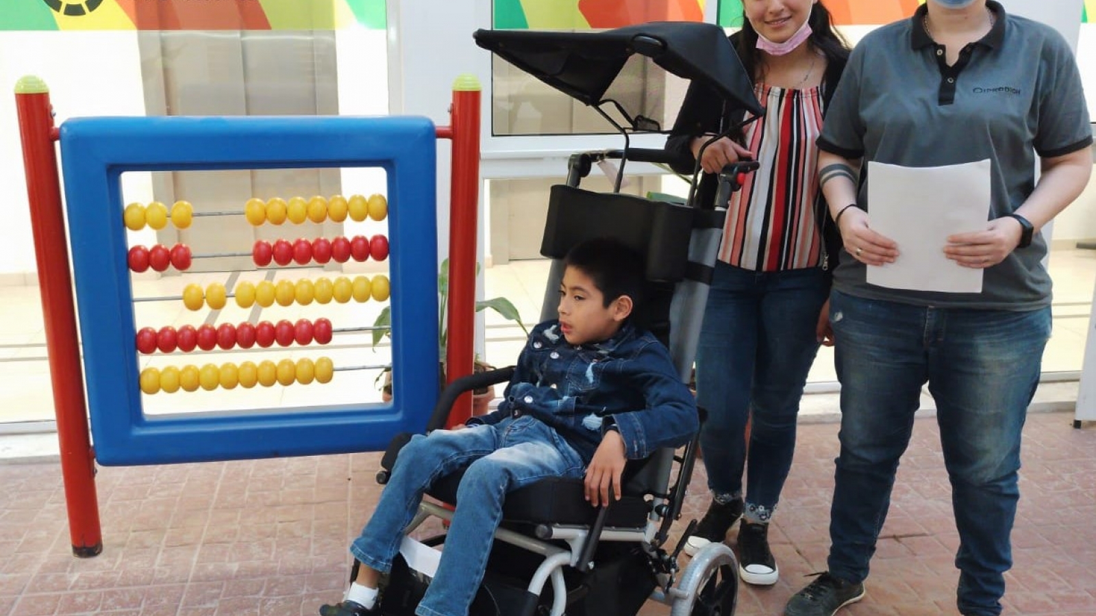 Personal del IPRODICH entregando silla de ruedas a nene con discapacidad
