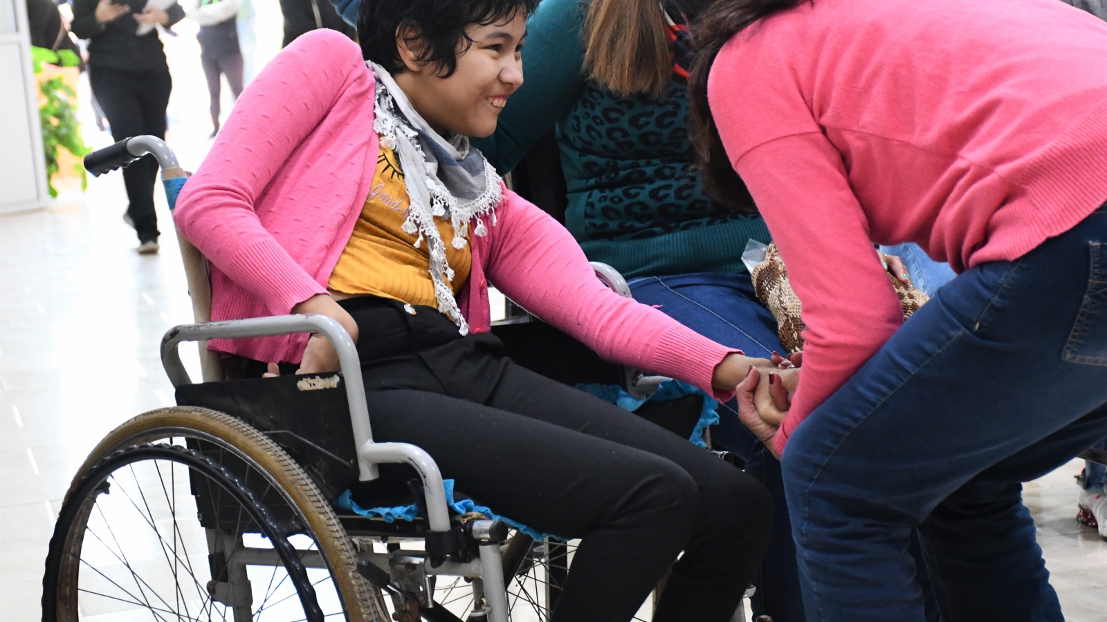 Nena en silla de ruedas siendo asistida