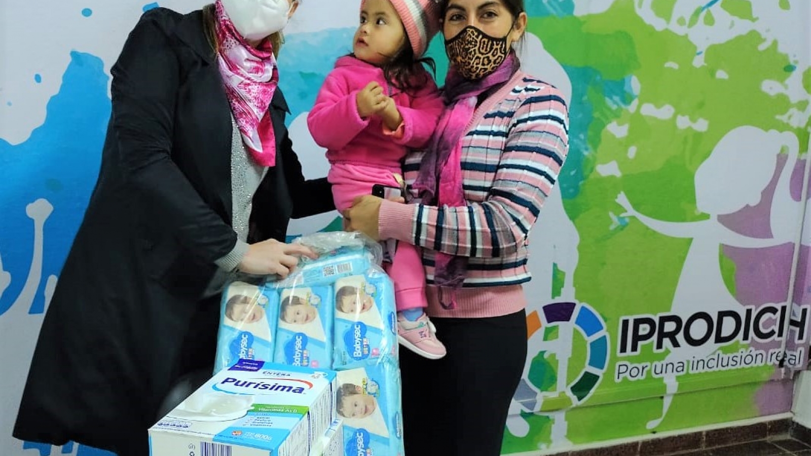 Equipo del IPRODICH entregando packs de leche en polvo a beneficiaria